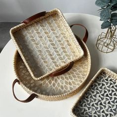 two wicker trays sitting on top of a white table next to a plant