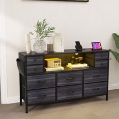 a black and brown dresser with some books on it's top shelf next to a potted plant