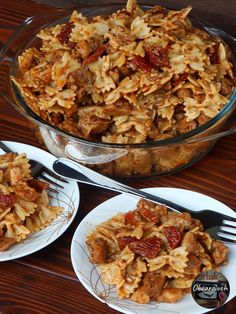 two plates filled with pasta and meat on top of a wooden table