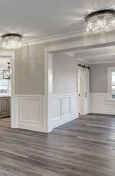 an empty living room with wood floors and chandelier hanging from the ceiling,