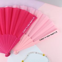 a pink fan sitting on top of a table next to a beaded bracelet and necklace