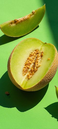 two pieces of melon sitting on top of a green surface next to each other