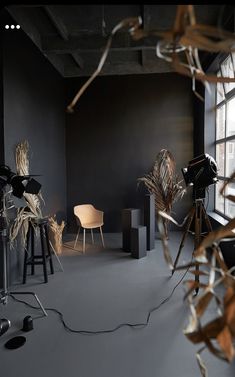 an empty room with black walls and wooden chairs in the corner, surrounded by dry grass