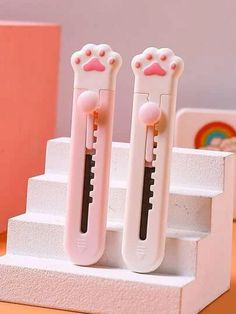 two plastic toothbrushes with pink noses on them sitting on some white steps next to each other