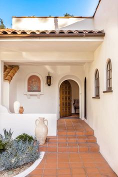 a white house with an orange tiled walkway leading to the front door and entryway