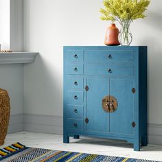 a blue cabinet with two doors and knobs on the front is next to a wicker basket