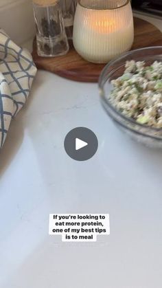 a bowl of food sitting on top of a white counter next to a glass vase