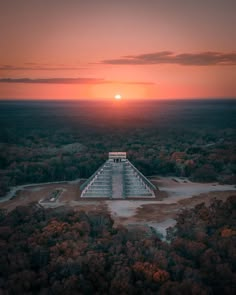 an aerial view of a pyramid in the middle of a forest at sunset or dawn