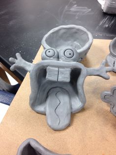 a clay sculpture of a face with eyes and mouth, sitting on top of a table