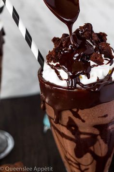 a chocolate milkshake with whipped cream and chocolate sauce on top is being drizzled