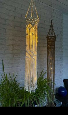 two lights hanging from the side of a brick wall next to a potted plant