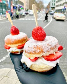 two donuts with strawberries and cream on top are sitting on a black glove