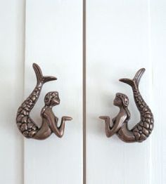 two metal mermaid door handles on white doors