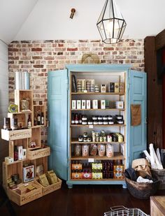 an open cabinet in the middle of a room with shelves full of food and drinks