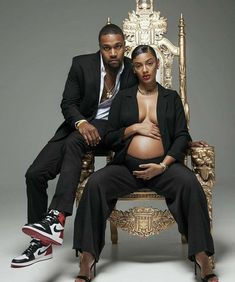 a pregnant woman sitting on top of a golden chair next to a man in a suit