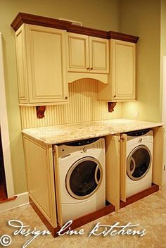 a washer and dryer are in the middle of a room with beige cabinets