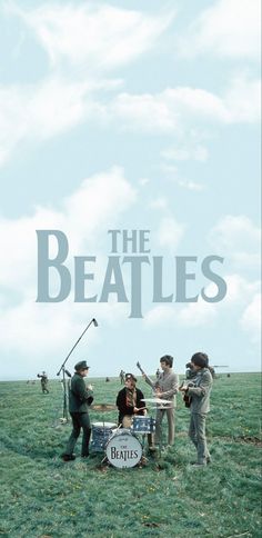 the beatles are playing in a field with people standing around them and one man is holding a microphone