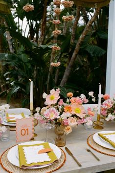 the table is set with place settings and flowers in vases on top of it