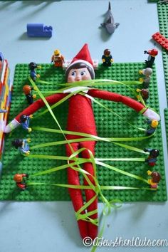 an elf is on the lego floor with his arms and legs wrapped in green string