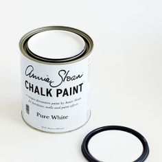 a white paint can with a black lid next to a blue and white object on a white surface