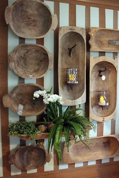 wooden bowls and trays are arranged on a wall with candles, flowers and greenery