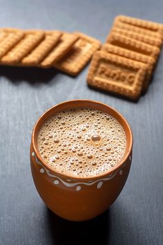 a cup of coffee and some crackers on a table