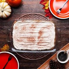 a cake sitting on top of a pan covered in frosting next to plates and cups