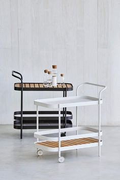 a white table with two bottles on it and a rolling cart in front of it