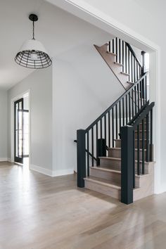 an empty living room with stairs leading up to the second floor and another open door