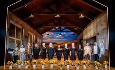 a group of people standing on top of a stage with sunflowers in front of them