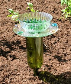 a green glass vase sitting on top of a dirt field