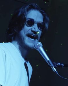 a man with sunglasses on singing into a microphone