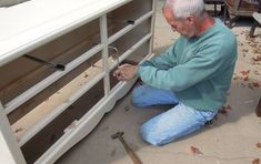 an older man is working on a white entertainment center with tools in front of him