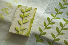 a piece of wood sitting on top of a table covered in green leafy fabric