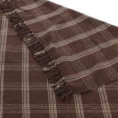 a brown and white checkered blanket with fringes on the edges, laying flat