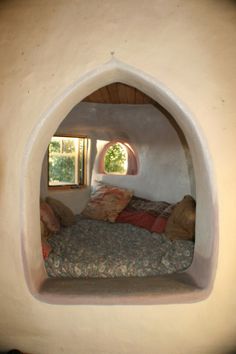 a bed sitting in the middle of a room with a window on one side and pillows on the other