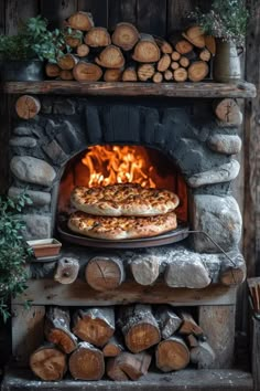 two pizzas cooking in an outdoor brick oven with firewood stacked on top and logs surrounding them