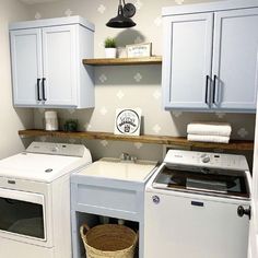 a washer and dryer in a small room with white cabinets on the wall