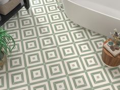 a bath tub sitting next to a white toilet in a bathroom with green tile on the floor