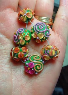 a hand holding some colorful beads in it's palm