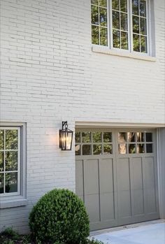 a white brick house with two garage doors and one light on the side of it