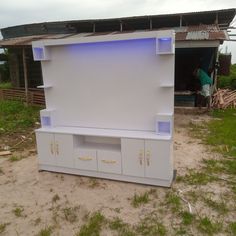 a white entertainment center sitting on top of a sandy beach