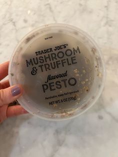 a hand holding a plastic container filled with food on top of a marble countertop