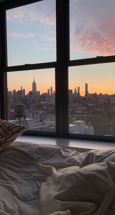 a bed sitting in front of a window with a view of the city below it