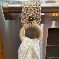 an oven door handle with a towel hanging from it's side and a wooden ring on the front