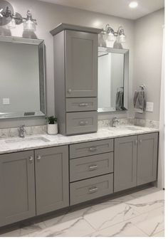 a large bathroom with two sinks, mirrors and cabinets in grey tones on the walls