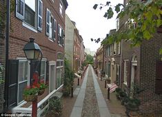 an alley way with brick buildings and potted plants