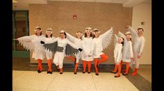 a group of women dressed in white and orange posing for a photo with angel wings