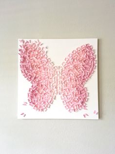 a butterfly made out of pink crepe paper on a white wall with the word love written in it