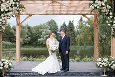 a bride and groom standing under a wooden gazebo